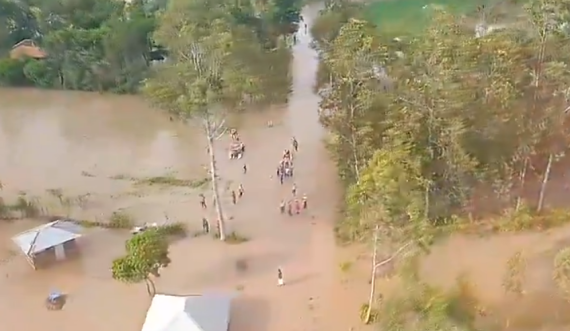 aerial view of human figures and submerged houses and trees in floodwaters.