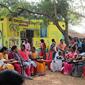 women dressed in bright colours sit outdoors sharing a meal