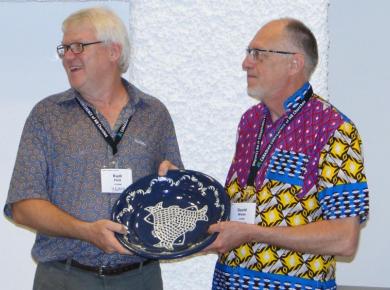 <p>David presents Rudi with a plate given to ICOMB from Mennonite World Conference (MWC). Photo courtesy of ICOMB.</p>