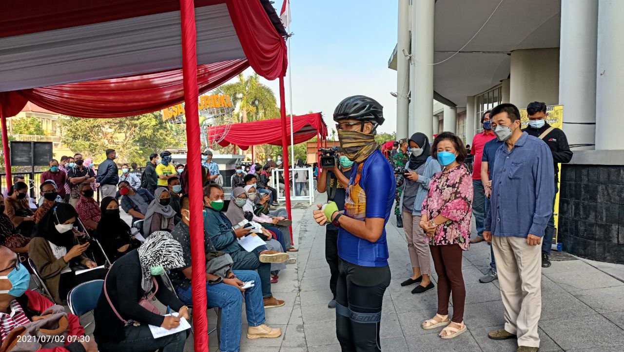 masked person addresses outdoor crowd