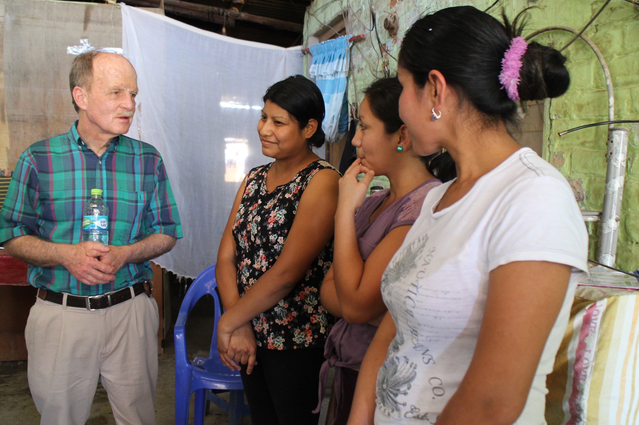 an older white man speaks with several young Indigenous women