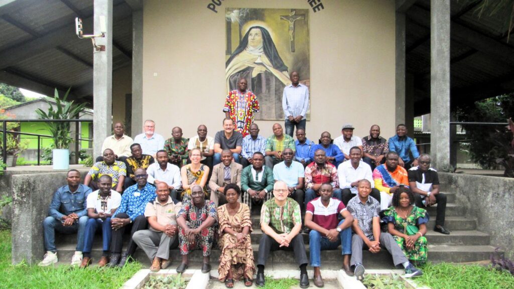 large group of mostly African men lined up for photo in front of building