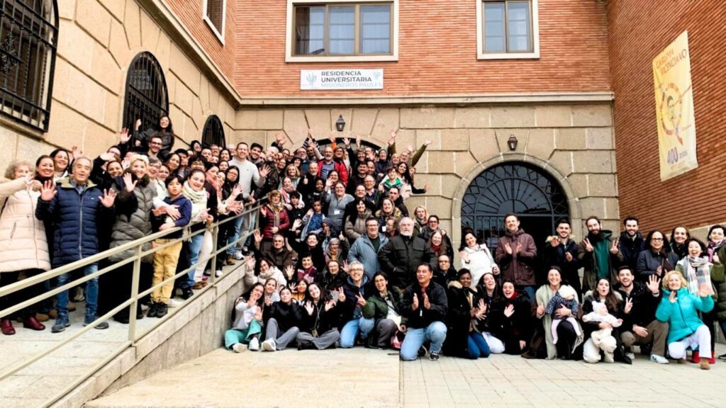 Large group of people lined up for photo in a courtyard of a brick building