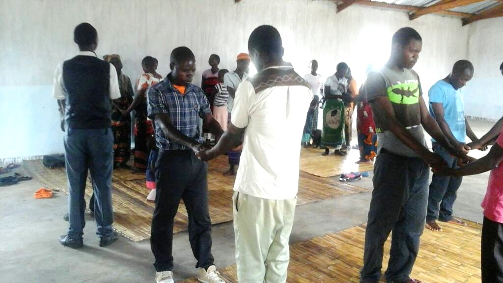 African men and women praying for each other in a pair