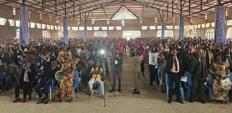 Interior shot of large church building in Africa full of people in formal attire.