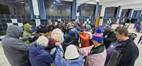 Throng of people gathered in a circle with laying hands
