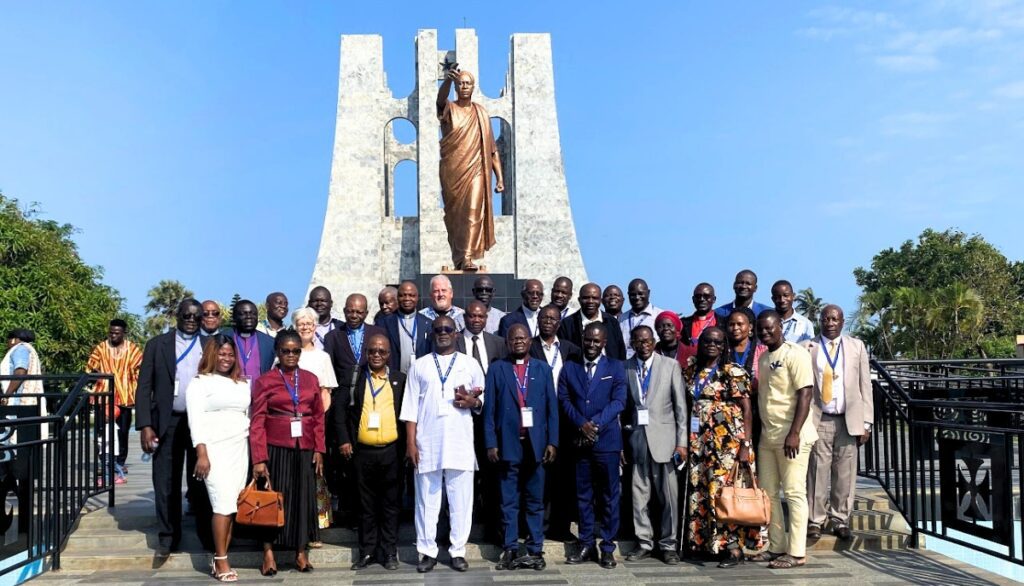A big group photo standing together in front of a statue