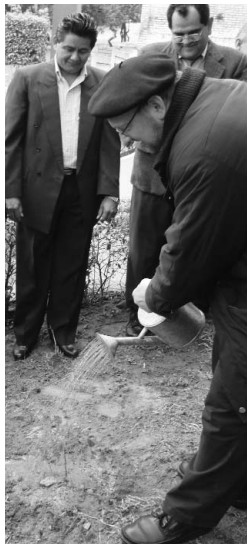 several men stand around another with a shovel, planting a tree